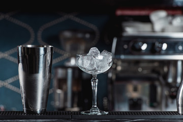 bar accessories shaker and full of ice cocktail glass on a bar background