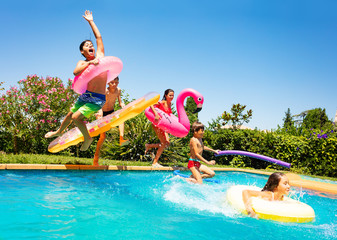 Happy friends jumping in pool on the vacations - obrazy, fototapety, plakaty