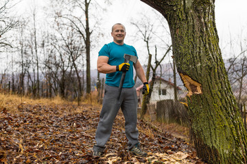 Lumberjack worker chopping down a tree breaking off many splinters in the forest with big axe.
