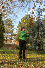 a woman trying to keep falling leaves in autumn