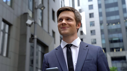 Inspired young man standing near business center, good news, successful startup