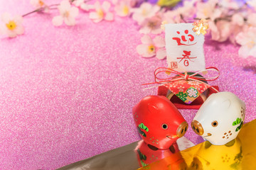 Glitter background with sakura cherry blossoms for japanese New Year's Cards with cute animal figurine of boar or pig and rice paper with handwriting ideograms Geishun which means Welcome Spring.