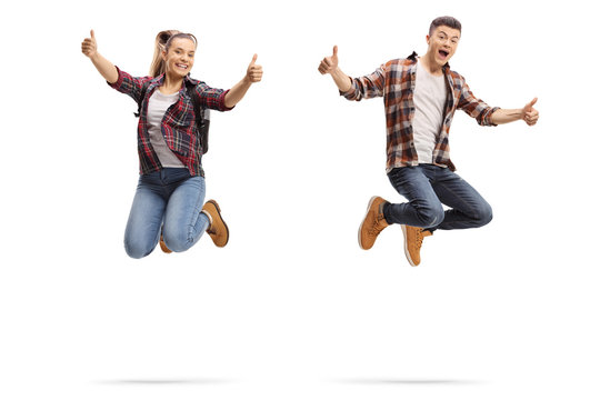 Teen boy and girl jumping and showing thumbs up