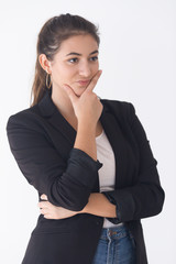 Smart female Caucasian manager standing in thinking position and supporting chin with hand. Young woman in formalwear looking aside and evaluating options. Startuper concept