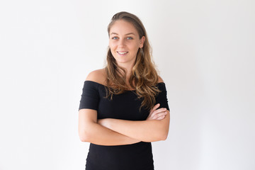 Fototapeta premium Young beautiful Caucasian woman smiling with crossed arms. Confident female organizer in black dress posing for corporate magazine. Successful event organizer concept
