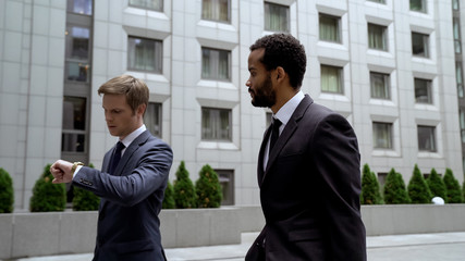 Men going to important business meeting, looking at watch, time management