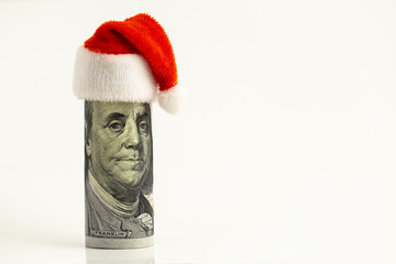 Humorous concept. President Franklin as Santa Claus. The hundred-dollar bill is hung up with a red cap at the top of its head. New Year or Christmas financial surprise. White background. Copy space.