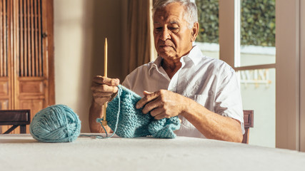 Retired senior man knitting warm clothes