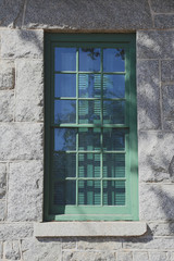 old window with green trim on a stone wall