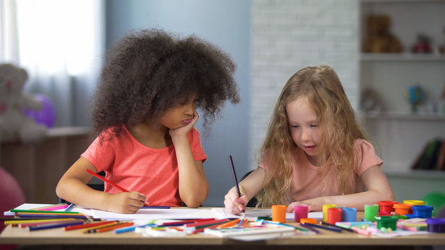 Happy preschool multiracial children drawing at table with colorful pencils