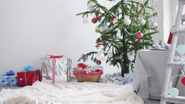 Christmas festive sparkly confetty falling down on the background of the Christmas tree and gifts boxes. slow motion. 3840x2160
