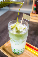 Green tea spinning on glass on brown wooden tray