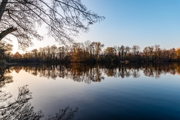 Crépuscule sur un étang en automne avec les arbre se reflétant dans l'eau