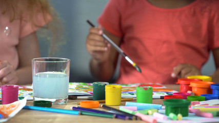 Multi-ethnic girls painting with gouache at workshop, art club, creativity