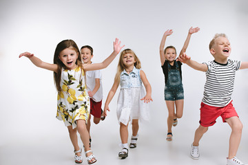 Obraz premium Group of fashion cute preschooler kids friends posing together and looking at camera on a white studio background. The friendship, fashion, summer concept. Space for text.