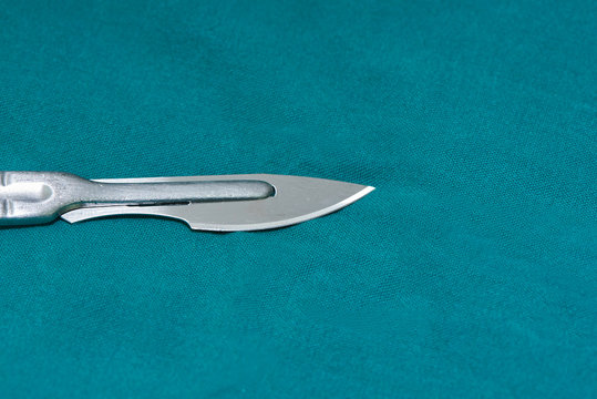 Close-up of surgical knife on green table