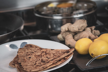 A round container for spices - with ginger and roti - cooking Indian food. 