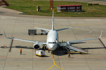 Modern twin engine civil airplane standing on parking place at ground maintenance at International...