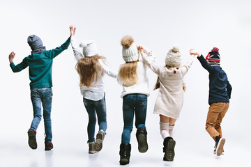 The back view of group of kids in bright winter clothes, isolated on white studio. Fashion, childhood, happy emotions concept