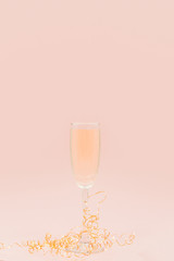 A glass of champagne with bubbles. Christmas balls and a golden lights on light abstract background.