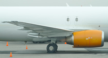 Yellow jet engine on a wing of white cargo plane.