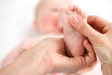 Mother does a foot massage to a newborn baby. mother's care. healthy lifestyle. Face is blurred in background. Close-up
