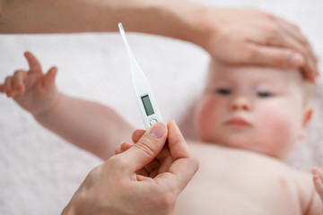 Close-up thermometer. Mother measuring temperature of her ill kid. Sick child with high fever...