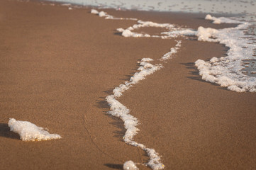 Close up white foam on the yellow sand, sea background,