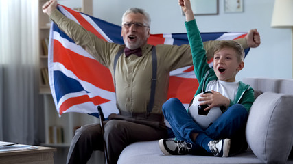 Granddad waving British flag, together with boy celebrate victory of soccer team