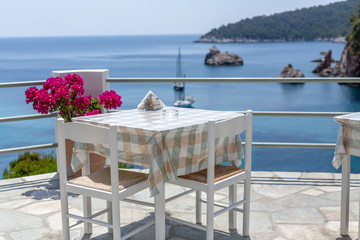 Restaurant tables waiting for customers by the sea outdoor terrace in Skopelos, Greece.