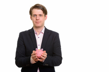 Handsome Caucasian businessman holding piggy bank and looking at camera