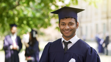 Smiling Hispanic graduate student rejoicing diploma, success, posing for camera