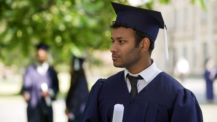 Graduate student looking into distance, nobody congratulating him, loneliness