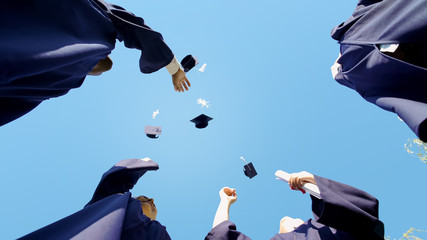 University graduates tossing up their square caps student tradition, bottom view