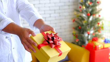 Men wear white long-sleeved shirt ,deliver happy giving you man hand holds yellow gifts box christmas concept new year.