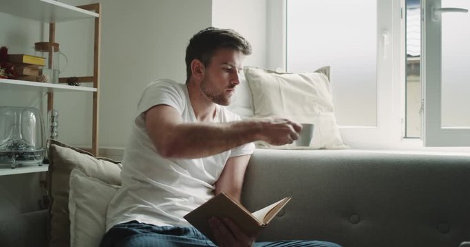 Perfect morning for a young guy reading a book and drinking coffee, on the sofa rustic design.