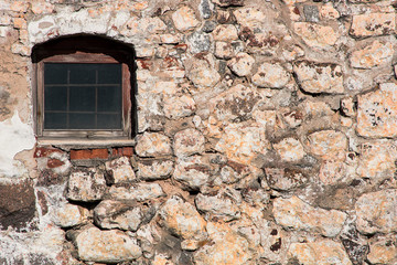 Fototapeta na wymiar Antique stone wall with a lattice window