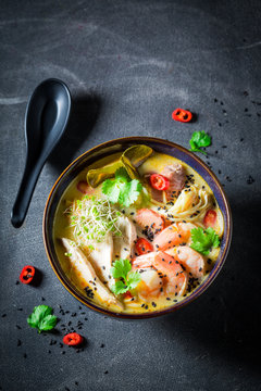 Malaysian Soup with chicken and shrimps on concrete table