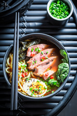 Tasty Ramen soup with noodles and spinach on black table