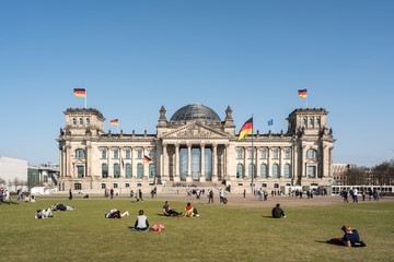 The facade of Reichstag building in Berlin, many unidentified visitors and tourists in foreground.