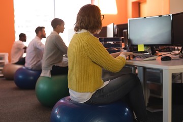 Business executives working at desk while sitting on exercise