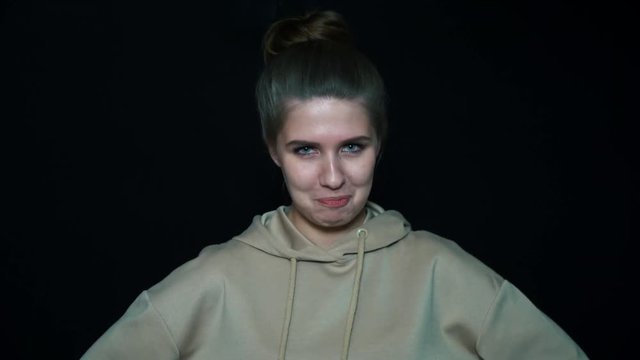 Portrait of a frowning girl, isolated on black background. Girl is very angry.