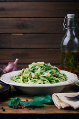 Spinach Fettuccine. Vegan pasta with spinach (Spinach Fettuccine Alfredo Pasta) on a white plate. Old wooden background. Copy space.