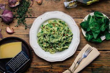 Spinach Fettuccine. Vegan pasta with spinach (Spinach Fettuccine Alfredo Pasta) on a white plate. Old wooden background
