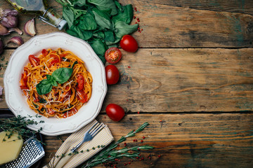 Spaghetti pasta with tomato sauce, parmesan and basil on a white plate. The classic tomato spaghetti: vegetarian tomato basil pasta. Old wooden background. Copy space.