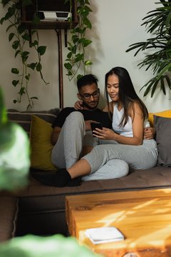 Couple using mobile phone on sofa in living room