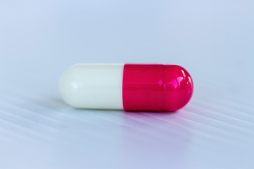 medicine concept; Pink-white capsule on white background.