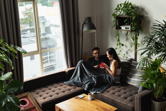 Couple having soup on sofa in living room