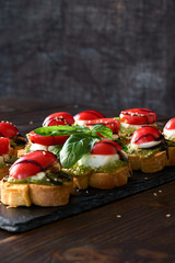caprese toasts on a black plate. vertical