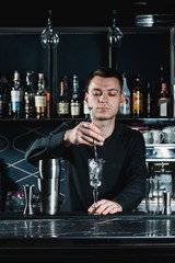 bartender making cocktail. Mixing ingredients in a glass. Bar on a background